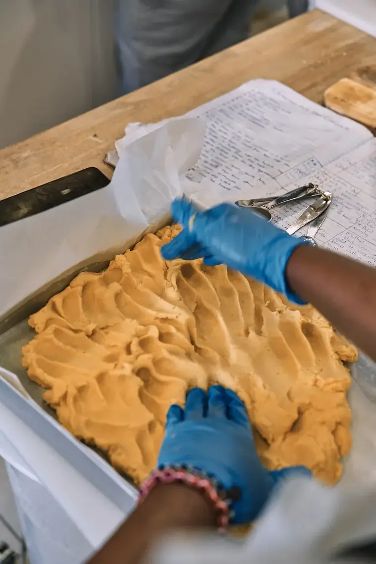 Hands spreading dough in a tray